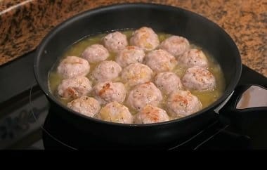 Sumergiendo las albóndigas selladas dentro de la salsa licuada en la olla